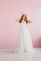 jovem noiva dentro branco vestir com flor guirlanda em dela cabeça posando dentro a estúdio foto