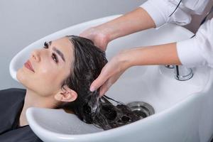 cabeleireiro profissional lavando o cabelo de jovem no salão de beleza. close-up do cabelo da mulher no salão de beleza, conceito de penteado foto