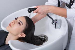 cabeleireiro profissional lavando o cabelo de jovem no salão de beleza. close-up do cabelo da mulher no salão de beleza, conceito de penteado foto