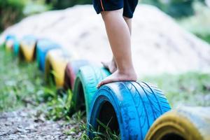 criança correndo com pneus no playground foto