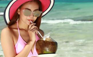 close-up de uma jovem em um biquíni vestido bebendo água de coco