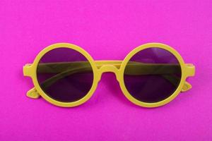 óculos amarelos isolados em fundo rosa foto