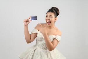 jovem noiva linda asiática postando com cartão de crédito na mão foto