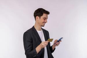 retrato do feliz jovem homem de negocios em pé usando Móvel célula telefone e segurando crédito banco cartão isolado em branco cor fundo estúdio foto