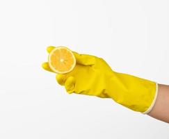 mão dentro uma amarelo látex limpeza luva detém metade uma limão em uma branco fundo foto