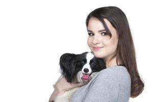 uma adorável jovem mulher é abraçando dela papillon cachorro e olhando para dentro a cummera. amor entre proprietário e cachorro. isolado em branco fundo. foto