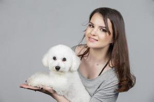 uma lindo jovem mulher é segurando dela bichon filhote de cachorro. amor entre proprietário e cachorro. a menina é jogando com a cachorro. foto