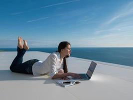 jovem relaxada em casa trabalhando no laptop foto