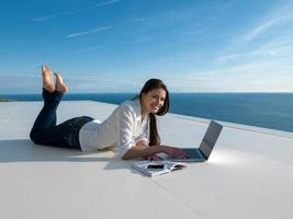 jovem relaxada em casa trabalhando no laptop foto