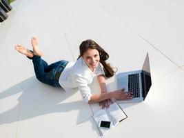 jovem relaxada em casa trabalhando no laptop foto