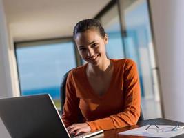 jovem relaxada em casa trabalhando no computador portátil foto