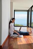 jovem relaxada em casa trabalhando no laptop foto