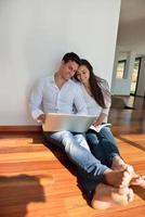 casal jovem relaxado trabalhando no computador portátil em casa foto