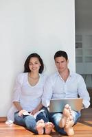 casal jovem relaxado trabalhando no computador portátil em casa foto