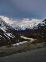 estrada sobre uma passagem na noruega, entre montanhas e neve foto