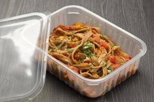 plástico almoço caixa com espaguete com tomate molho e cebolinha foto