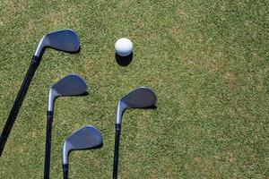 clube de golfe e bola de golfe na grama verde foto