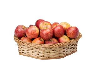 maçãs vermelhas na cesta de vime em fundo branco isolado foto
