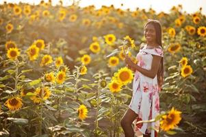 bela jovem negra usar pose de vestido de verão em um campo de girassol. foto