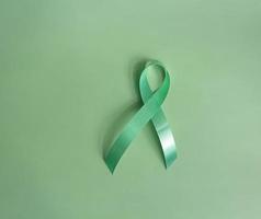 verde fita uma símbolo do a global mulheres seio Câncer campanha. oncológico doença prevenção e fêmea assistência médica. tiro isolado em verde fundo foto