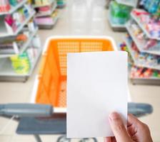 mão segurando compras Lista papel com compras carrinho às supermercado foto