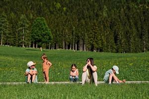 mãe sentada com crianças no caminho em prado alpino em untertauern, áustria. foto