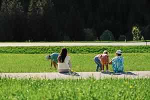 costas do mãe sentado com crianças em caminho dentro alpino Prado às untertauern, Áustria. foto