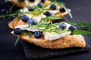 Bruschetta. torrada crostini com fresco bagas mirtilo e mel, brie queijo, Rúcula. italiano cozinha foto