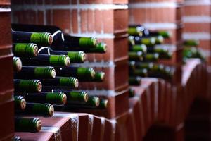 garrafas de vinho em repouso empilhadas em um cofre de tijolos de pedra