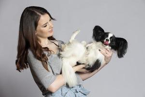 fofa jovem mulher segurando dela papillon filhote de cachorro. amor entre proprietário e cachorro. a menina é jogando com a cachorro. foto