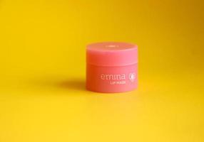 oeste Jacarta, Indonésia - fevereiro 10º, 2023 - emina lábio mascarar dentro pequeno Rosa recipiente isolado em amarelo fundo. menina beleza pele Cuidado produtos, fácil para levar para viagem. frente visualizar. foto