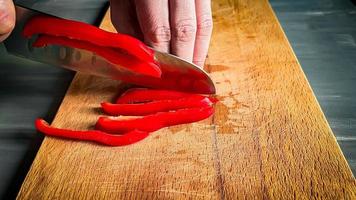 fatiamento vermelho Pimenta. mãos segurando Pimenta foto