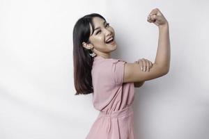 animado ásia mulher vestindo uma Rosa blusa mostrando Forte gesto de elevação dela braços e músculos sorridente orgulhosamente foto