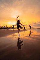 uma grupo do ásia mulheres é em pé em a de praia dentro Preto roupas e fazendo balé movimentos dentro uníssono foto