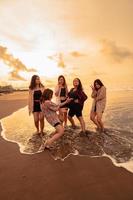 uma grupo do indonésio mulheres apreciar a de praia alegremente quando elas Conheça seus amigos às a feriado momento foto