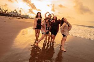 uma grupo do ásia mulheres desfrutando seus feriado muito louco com seus amigos e com uma cheio expressão do tolice em a de praia foto