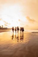 uma grupo do ásia adolescentes dentro camisas corrida com seus amigos com muito alegre expressões em a de praia foto