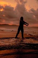a ásia mulher quem é jogando e dançando em a de praia com Forte ondas foto