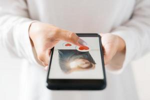 dia dos namorados dia e amor dia conceito, mulher dedo tocante coração ícone em tela dentro Smartphone aplicativo, feliz mulher postagem amor coração emoji ícone botão, procurar aplicativo conectados casal. foto