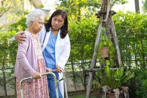 médico, ajuda e cuidado mulher idosa asiática sênior ou idosa usar walker com forte saúde ao caminhar no parque em feliz feriado fresco. foto