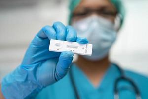 médico asiático em traje de EPI mostra resultado positivo do teste com kit de teste de antígeno de saliva para verificar o coronavírus covid19 no hospital. foto