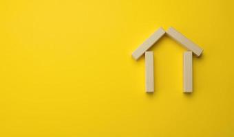 de madeira miniatura casa em uma amarelo fundo. a conceito do comprando e vendendo uma casa, alugando e locação real Estado foto