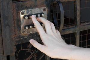 fêmea mão dials a código em uma vintage velho combinação porta trava foto