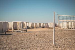 arenoso de praia com branco tendas e uma voleibol tribunal. de praia voleibol. verão período de férias foto