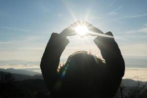 mulher feliz alpinista com os braços abertos levantados ao pôr do sol foto