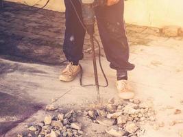 fechar acima trabalhador homem pedreiro perfuração cimento concreto chão com máquina foto