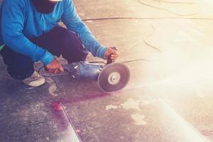 fechar acima mão homem corte concreto chão com máquina. foto