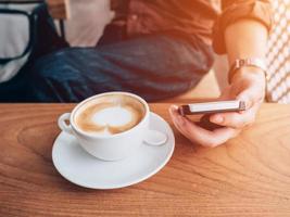 fechar acima mão homem usando telefone dentro café fazer compras com vintage filtro. foto