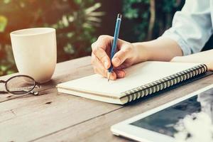 fêmea mão com lápis escrevendo em caderno. mulher mão com lápis escrevendo em caderno às café fazer compras. foto