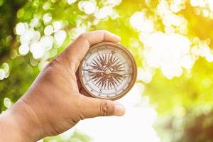 bússola em mão e verde bokeh com luz solar. foto